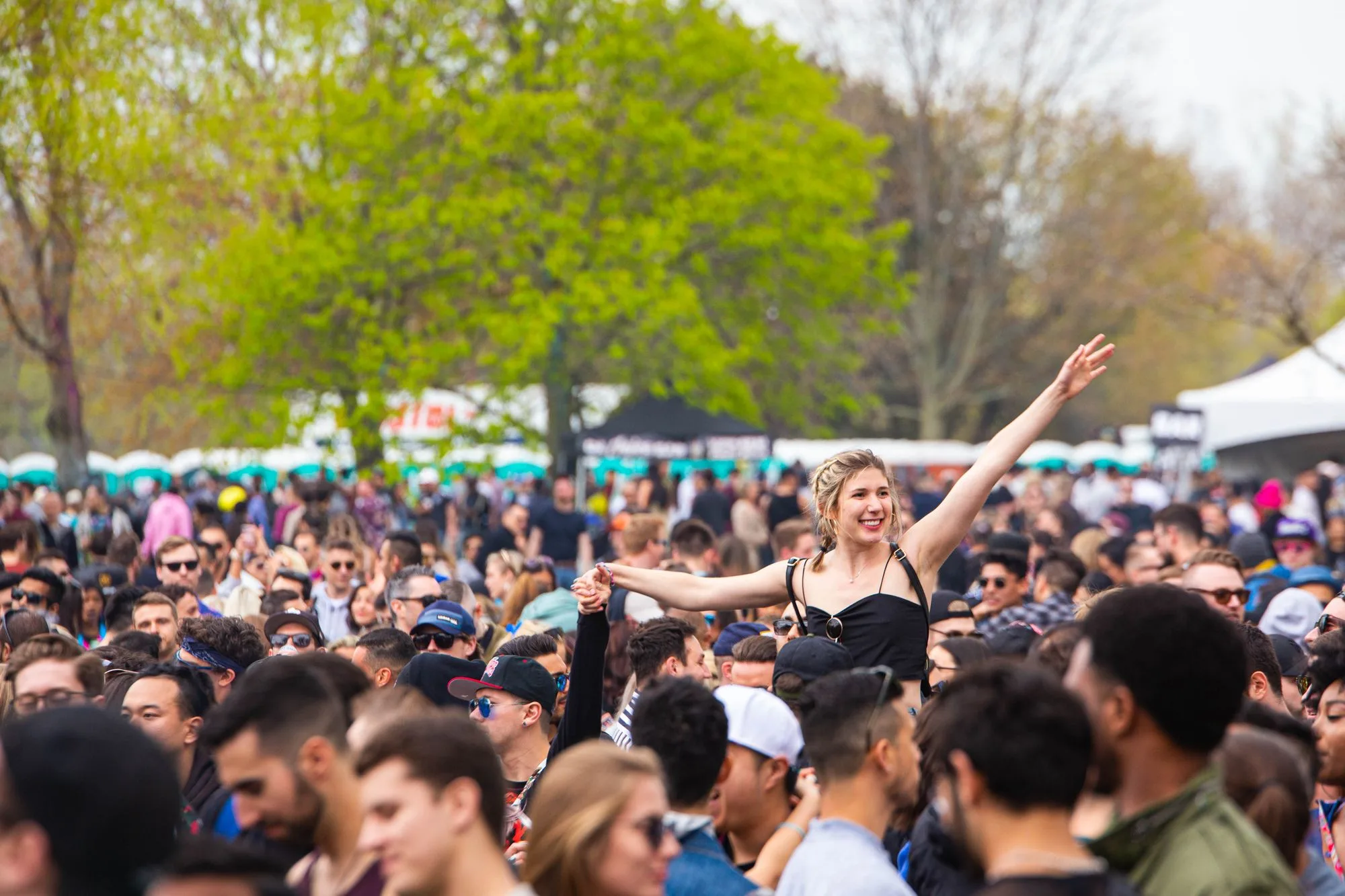 Un festival de música al aire libre de día, con público bajo árboles en primavera